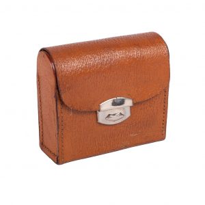In Hazelnut pigskin case with silver latch. Includes two brushes with wooden handles and a polishing cloth.