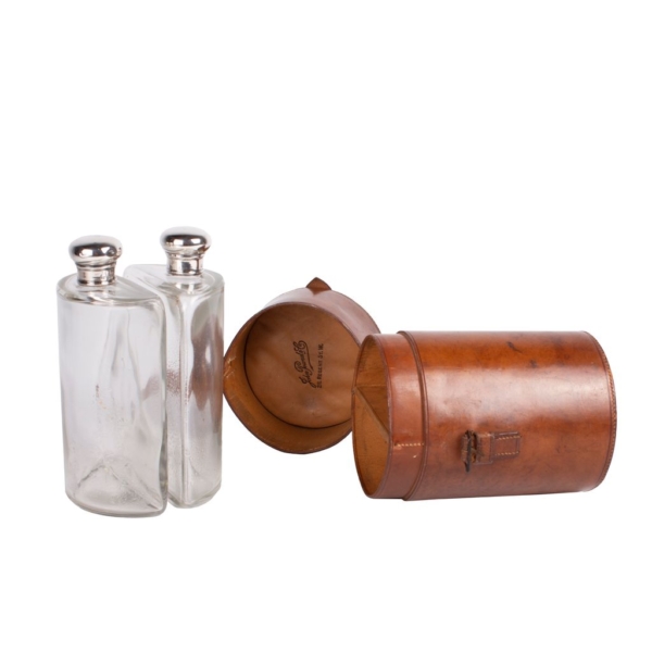 Round decanter signed by John Pound & Co. contains two glass jars with punched silver stoppers and a leather case.